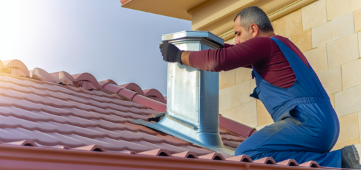 A roofer installing a steel chimney pipe on a house